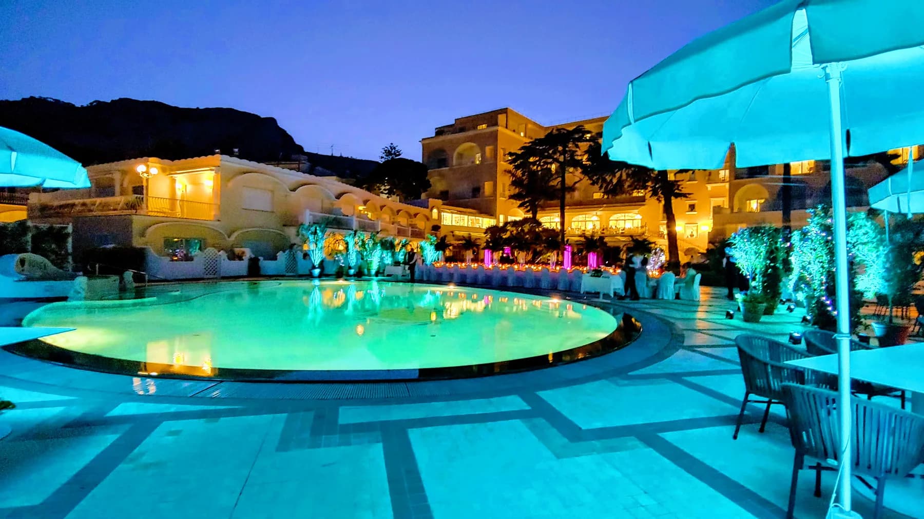Poolside gala at blue hour in Capri with hotel uplighting and dinner setup around the round pool